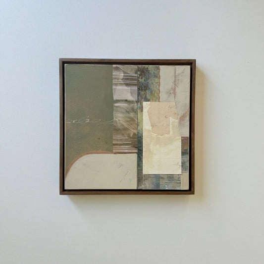 A framed abstract mixed-media collage painting hanging on a light gray wall. The artwork features a dark brown wooden frame and contains blocks of muted olive green, beige, cream, gray, and textured paper details.